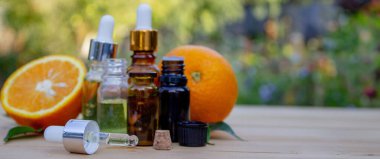 Doğanın arka planında bir şişe aromatik esans ve taze portakal.
