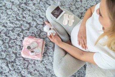 Hamile bir kadın bebek eşyaları toplar. Seçici odaklanma. Ev.