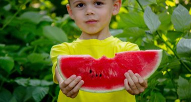 Bir çocuk yazın lezzetli bir karpuz yer.