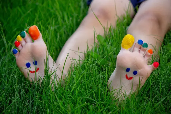a smile drawn with paints on a child\'s legs.