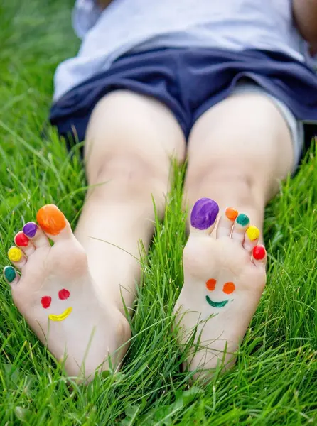 a smile drawn with paints on a child's legs.
