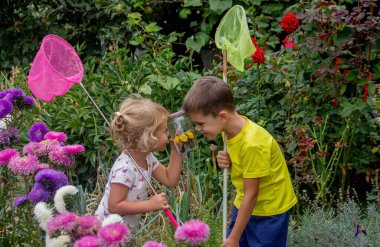 İki mutlu çocuk kelebekleri yakalar ve hayranlık duyar.