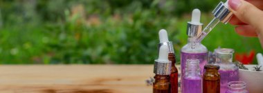 Ahşap arka planda cam bir şişe lavanta yağı.