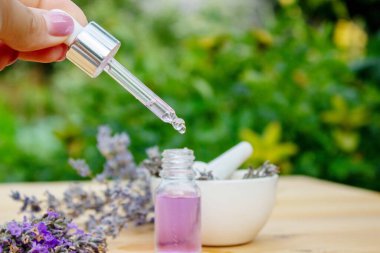 Ahşap arka planda cam bir şişe lavanta yağı.