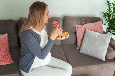 Hamile bir kadın tatlı bir çörek yer. Seçici odaklanma. Yiyecek..