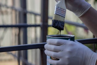 Metal bir boruyu boyayan bir elin yakın çekimi. Seçici odak.