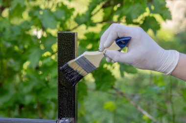 Metal bir boruyu boyayan bir elin yakın çekimi. Seçici odak.