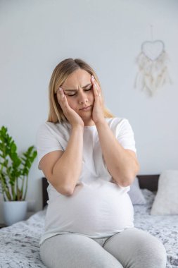 Hamile kadının başı ağrıyormuş. Seçici odaklanma. Ev.