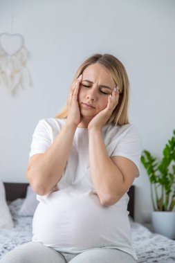 Hamile kadının başı ağrıyormuş. Seçici odaklanma. Ev.