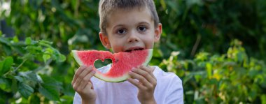 Çocuk doğanın arka planında karpuz yiyor. Seçici odak.