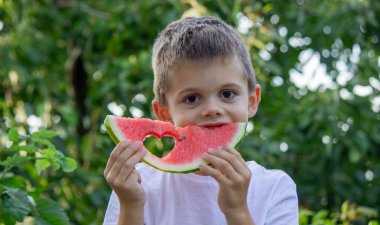Çocuk doğanın arka planında karpuz yiyor. Seçici odak.