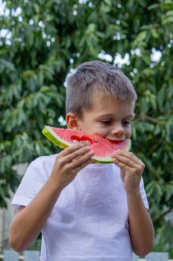 Çocuk doğanın arka planında karpuz yiyor. Seçici odak.