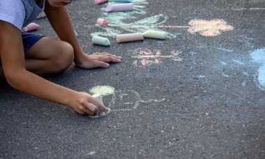Çocuk asfalta tebeşirle çiziyor. Seçici odak.