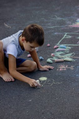 Çocuk asfalta tebeşirle çiziyor. Seçici odak.