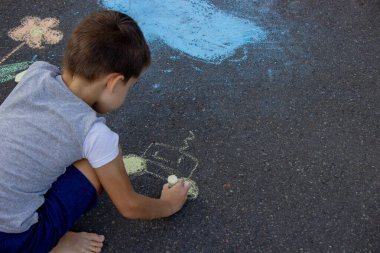 Çocuk asfalta tebeşirle çiziyor. Seçici odak.