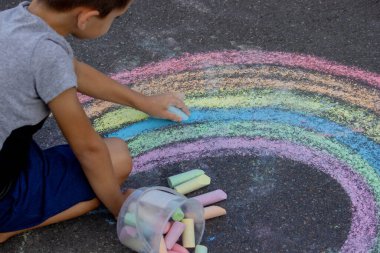 Çocuk asfalta tebeşirle çiziyor. Seçici odak.
