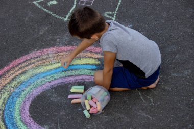 Çocuk asfalta tebeşirle çiziyor. Seçici odak.