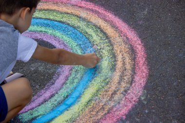 Çocuk asfalta tebeşirle çiziyor. Seçici odak.