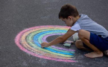 Çocuk asfalta tebeşirle çiziyor. Seçici odak.