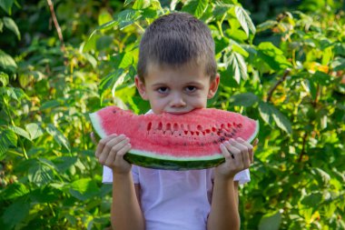 Çocuk arka planda bir karpuz yiyor. Seçici odak.