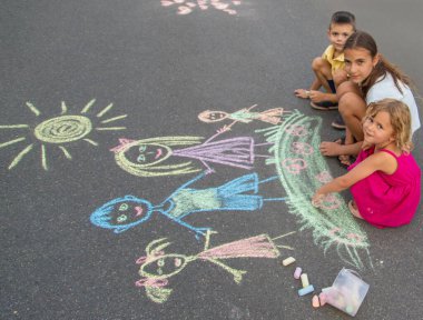 Çocuklar tebeşirle bir aile çizerler. Seçici odak.