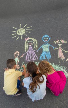 Çocuklar tebeşirle bir aile çizerler. Seçici odak.