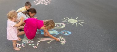 Çocuklar tebeşirle bir aile çizerler. Seçici odak.
