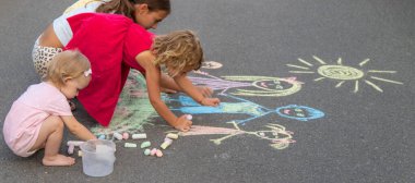 Çocuklar tebeşirle bir aile çizerler. Seçici odak.