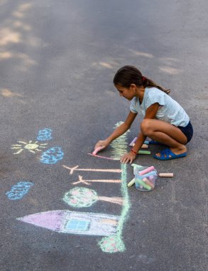 Bir çocuk asfalta tebeşirle resim çizer. güzel resim