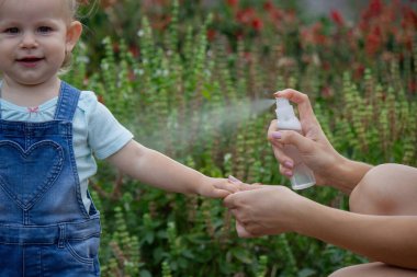 Anne çocuğun vücuduna sprey sprey sıkar. Seçici odak.