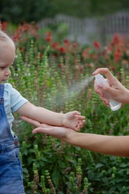Anne çocuğun vücuduna sprey sprey sıkar. Seçici odak.
