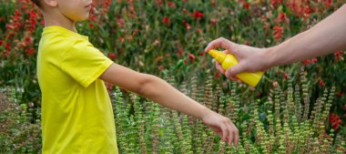 Anne çocuğun vücuduna sprey sprey sıkar. Seçici odak.