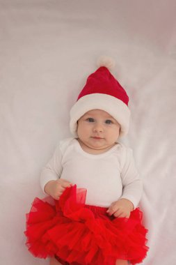 Işıklı arka planda Noel Baba şapkalı küçük kız. Tatil.