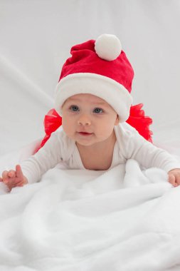 Işıklı arka planda Noel Baba şapkalı küçük kız. Tatil.