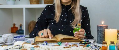 Woman fortune teller reads a book of spells. Selective focus. People.