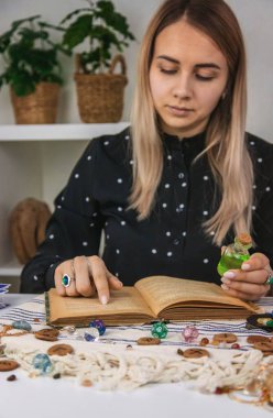 Woman fortune teller reads a book of spells. Selective focus. People.