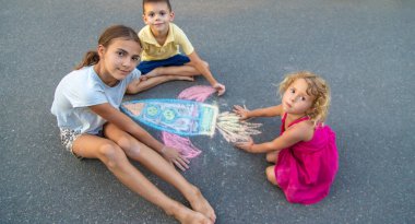 Çocuklar asfalta roket çiziyor. Seçici odak.