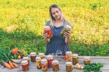 Bir kadın kavanozlarda sebze saklar. Seçici odak.