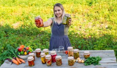 Bir kadın kavanozlarda sebze saklar. Seçici odak.