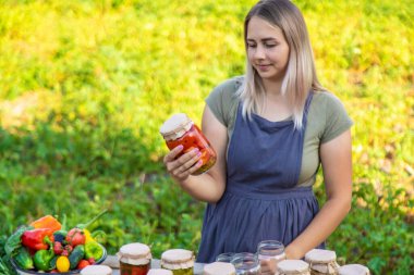 Bir kadın kavanozlarda sebze saklar. Seçici odak.