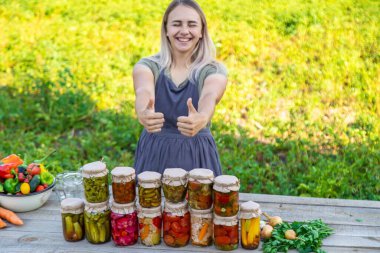 Bir kadın kavanozlarda sebze saklar. Seçici odak