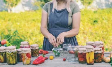 Bir kadın kavanozlarda sebze saklar. Seçici odak