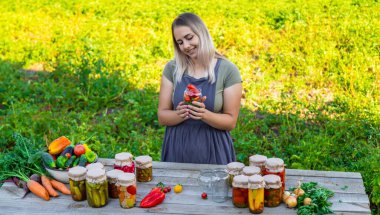Bir kadın kavanozlarda sebze saklar. Seçici odak