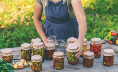 Bir kadın kavanozlarda sebze saklar. Seçici odak.