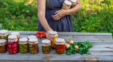 Bir kadın kavanozlarda sebze saklar. Seçici odak