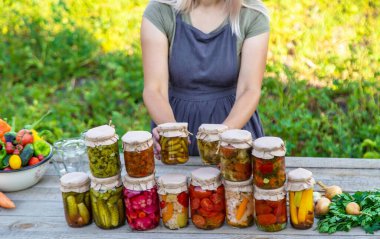 Bir kadın kavanozlarda sebze saklar. Seçici odak