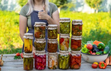 Bir kadın kavanozlarda sebze saklar. Seçici odak