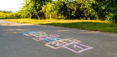 Klasik oynayan çocuklar, asfalta renkli tebeşirle çizilmiş. Çocuklar için yaz eğlencesi