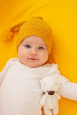 Sarı arka planda yatan gülümseyen bebek. Bebeğim.