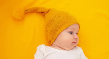 Sarı arka planda yatan gülümseyen bebek. Bebeğim.